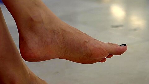 Beautiful Female Asian Feet With Black Nail Polish At The Shopping Mall