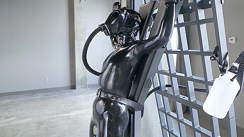 Latexgirl Tied To Cross And Vibed While Rebreather :: Latex bondage scene with masked woman restrained