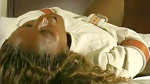 Tigra struggles in a straitjacket and leather cuffs